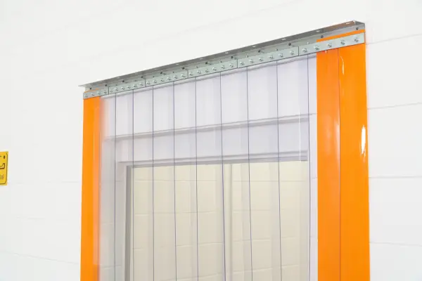 Clear PVC strip curtain door kit with orange edge strips installed in a doorway